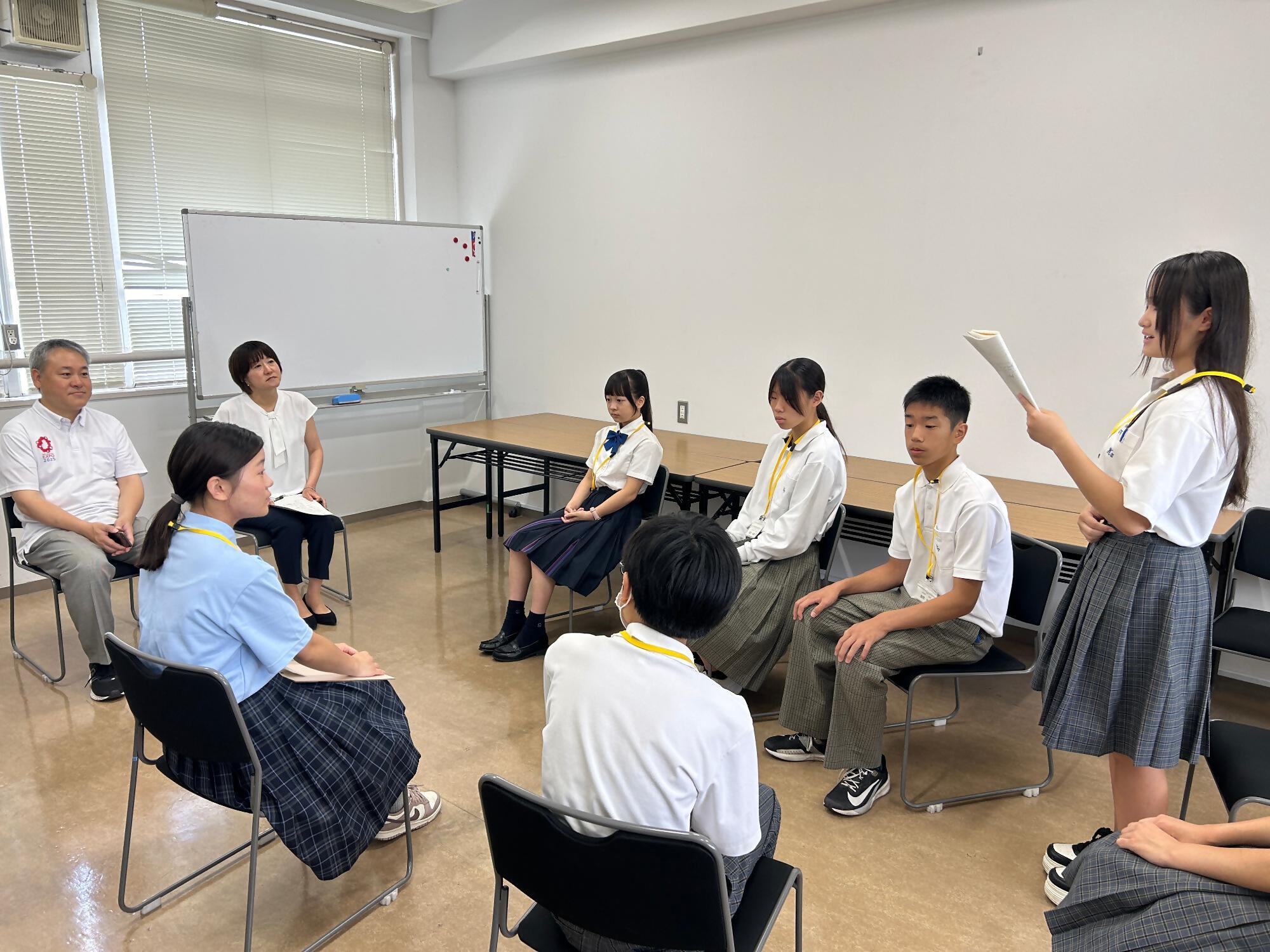 研修生達が輪になって一人ずつ英語で発表をしている写真です