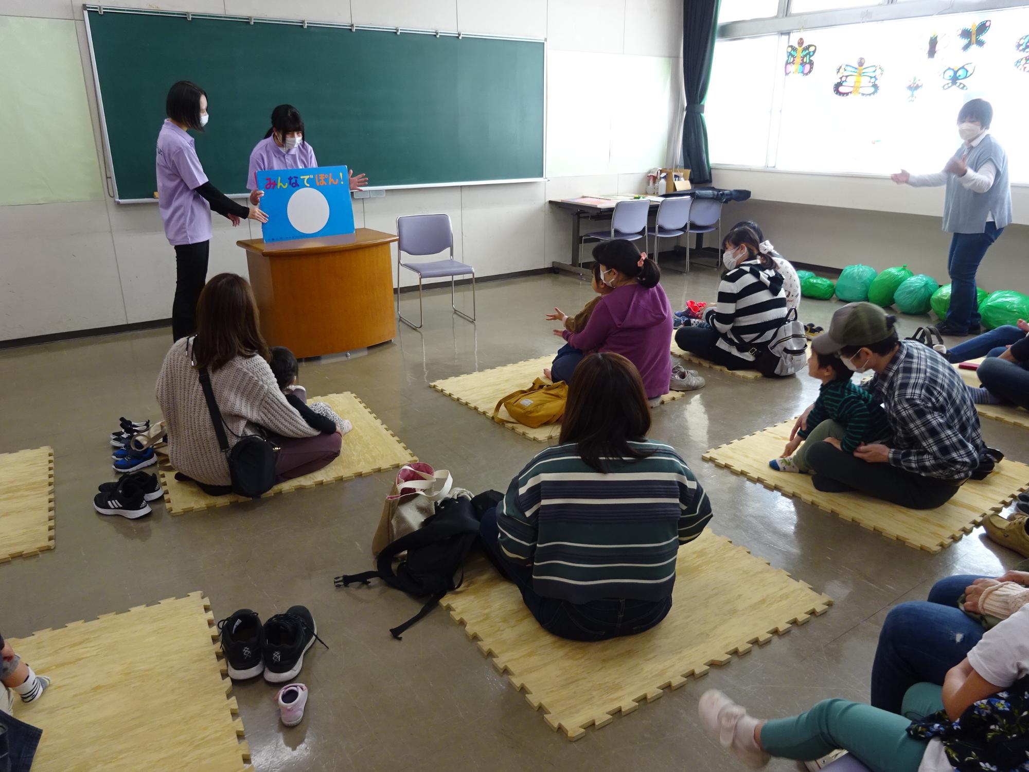大阪信愛学院大学の学生が参加者の子どもたちに大型絵本の読み聞かせをしている様子