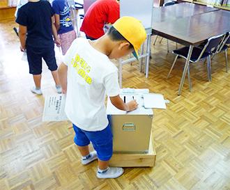 投票箱に投票用紙を入れる児童の写真